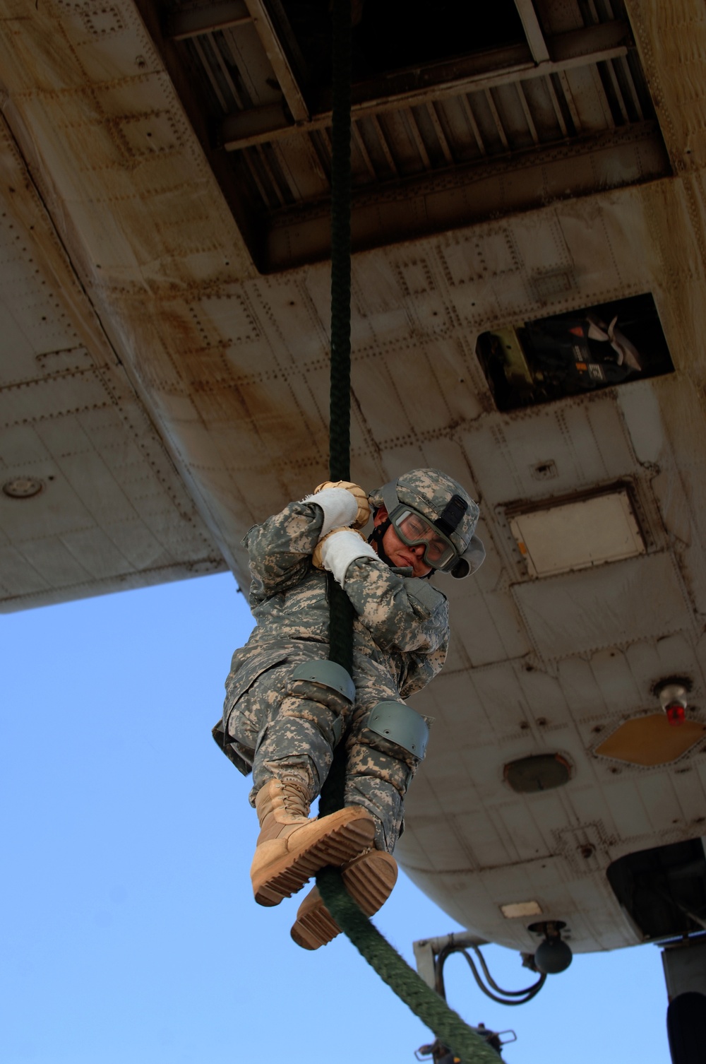 A U.S. Army soldier fast ropes from a helicopter.