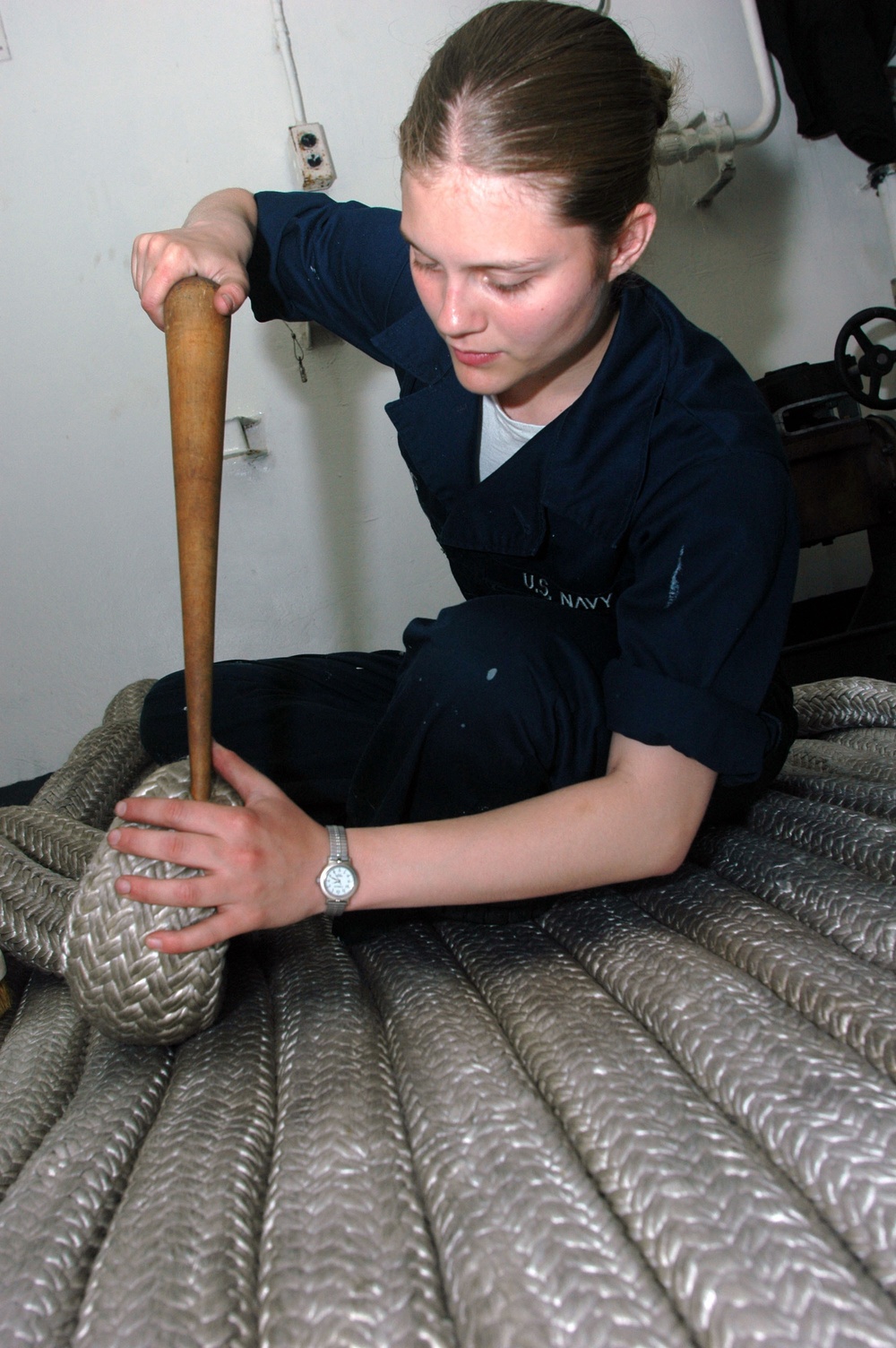 U.S. Navy Seaman Jamie Lewis uses a fid to repair a snag in a mooring line.