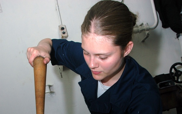 U.S. Navy Seaman Jamie Lewis uses a fid to repair a snag in a mooring line.