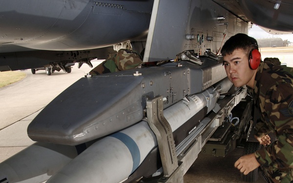 Staff Sgt. Randy Broome signals a jammer operator to move a BRU-61 bomb rack forward.