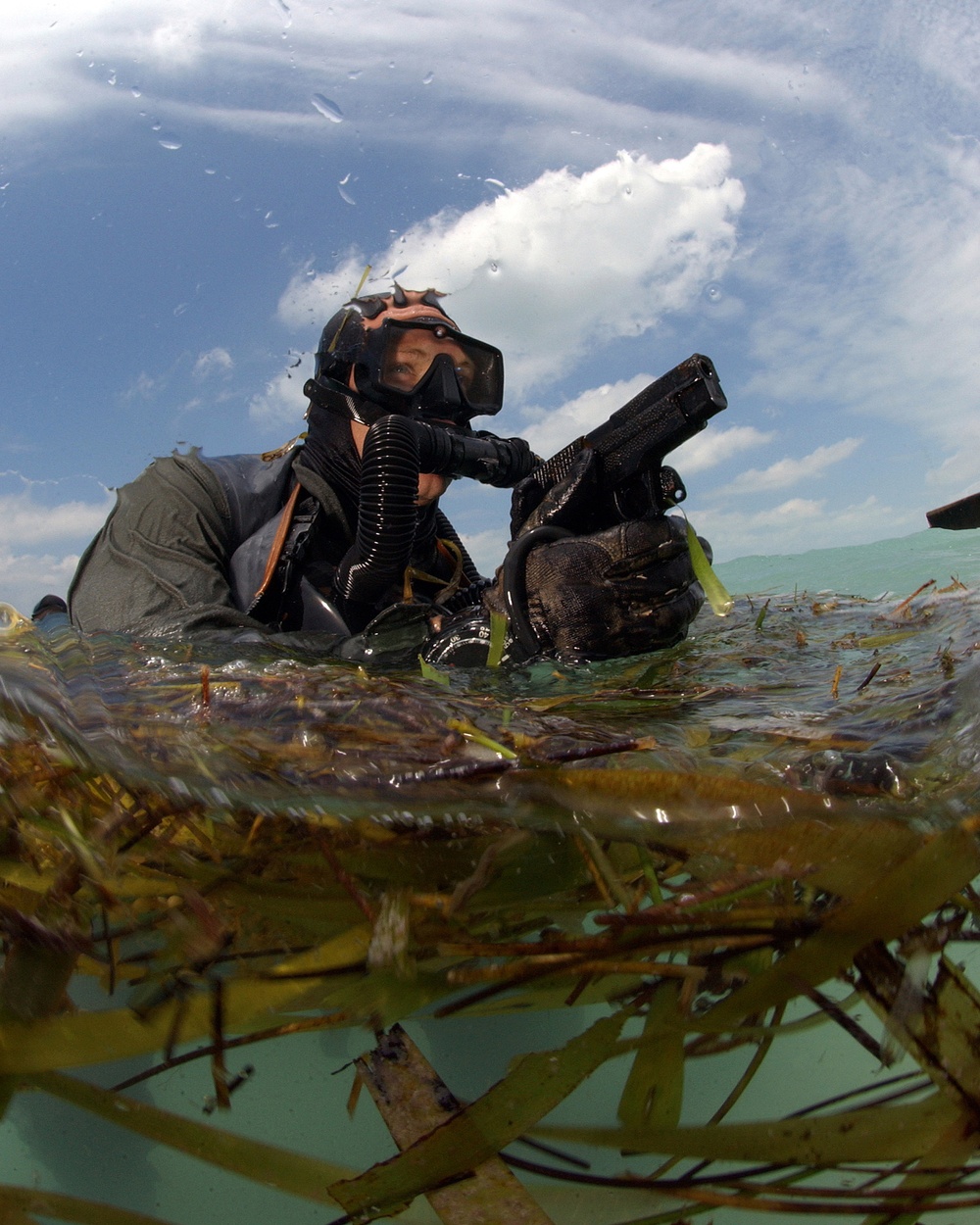 A U.S. Navy SEAL surfaces with his weapon drawn.