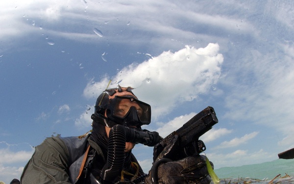 A U.S. Navy SEAL surfaces with his weapon drawn.