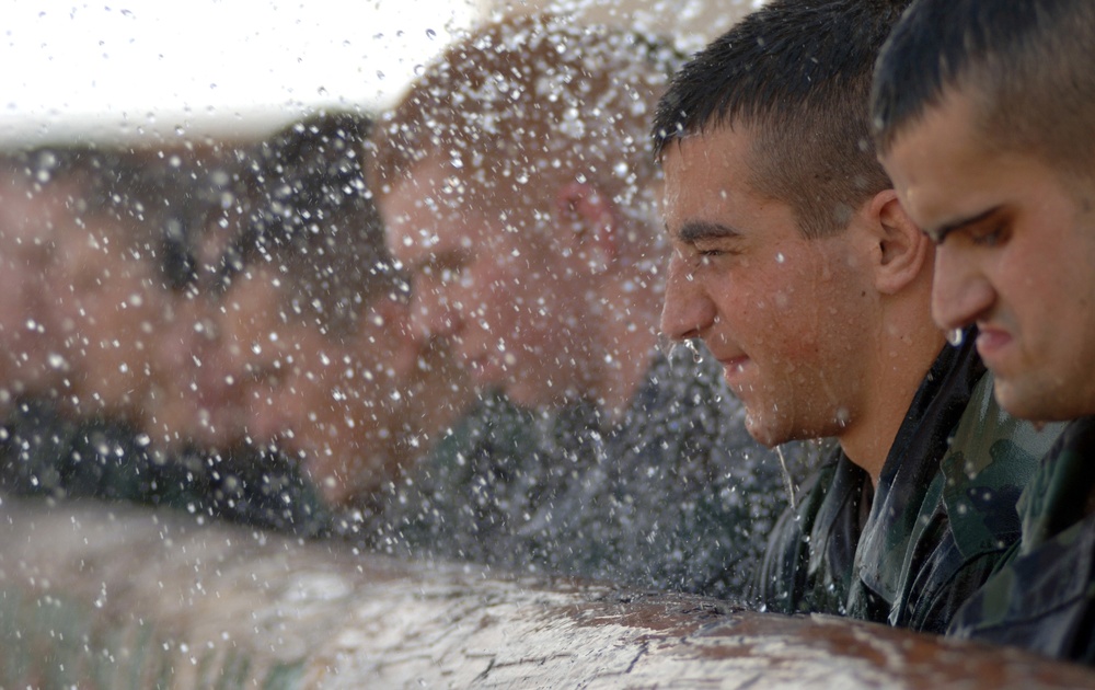 Cadres soak pararescue trainees as they try to carry a heavy training log.