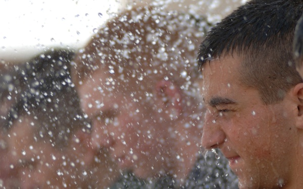 Cadres soak pararescue trainees as they try to carry a heavy training log.