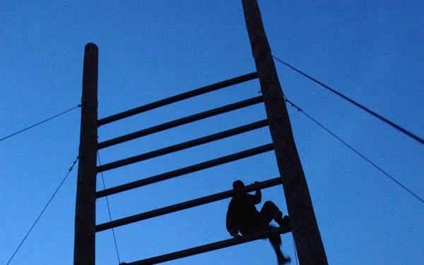Two pararescue trainees run through an obstacle course.