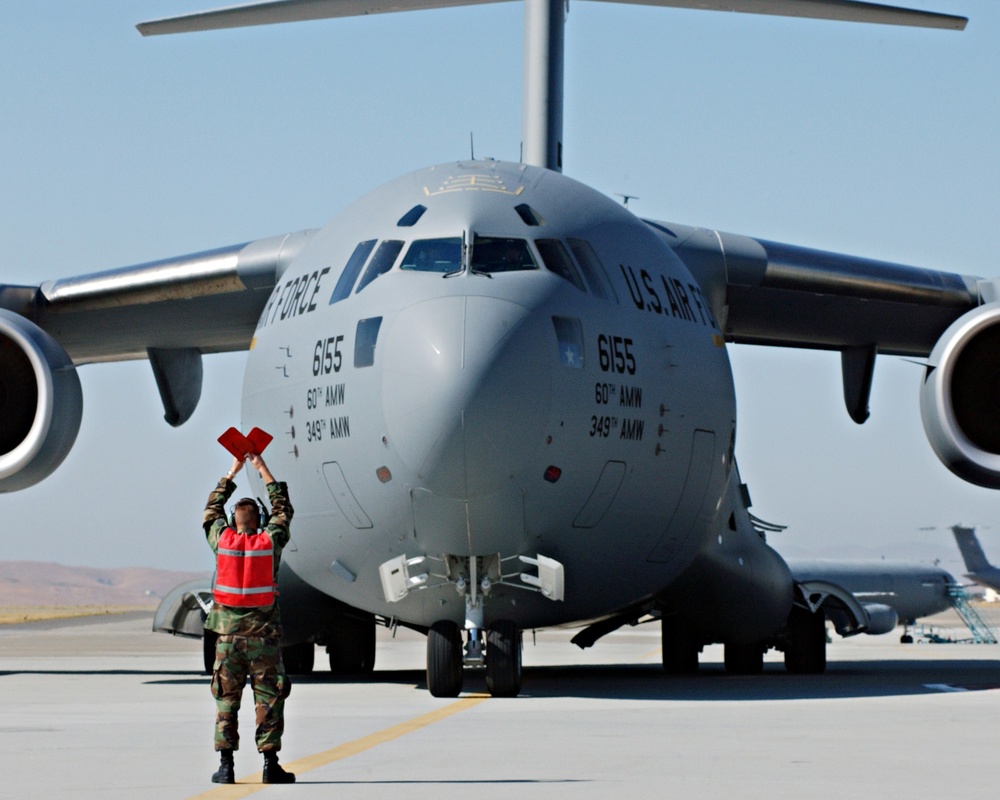 Staff Sgt. Jeffrey Eckert marshals a C-17 Globemaster III aircraft into its parking location.
