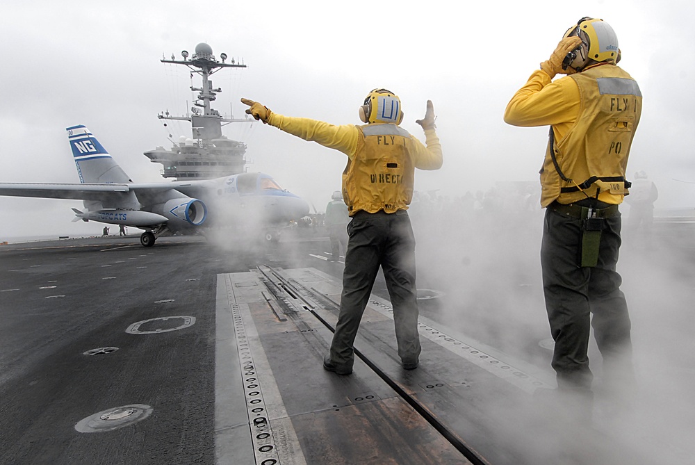 A Navy flight deck director guides the pilot of an S-3B Viking aircraft.