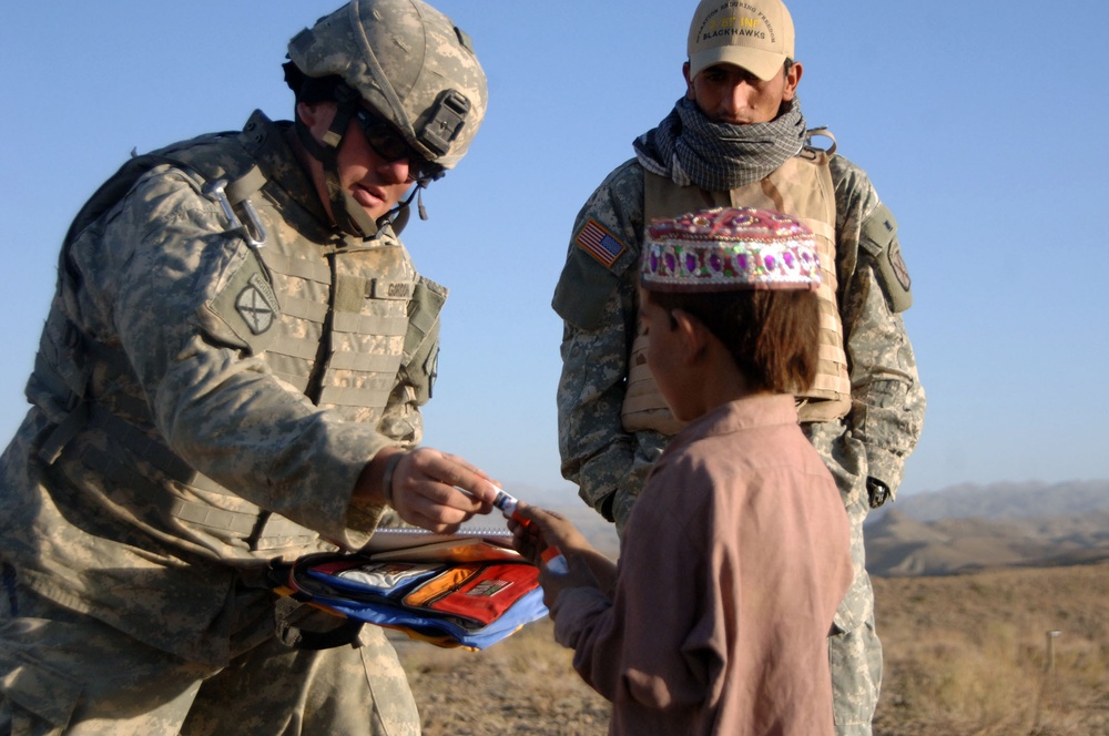 U.S. Army 1st Lt. Dan Gordon hands an Afghan boy school supplies.