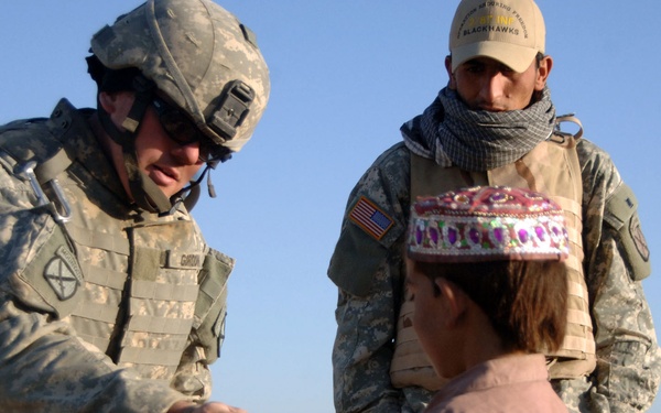 U.S. Army 1st Lt. Dan Gordon hands an Afghan boy school supplies.