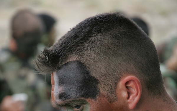 A U.S. Air Force airman applies camouflage makeup.
