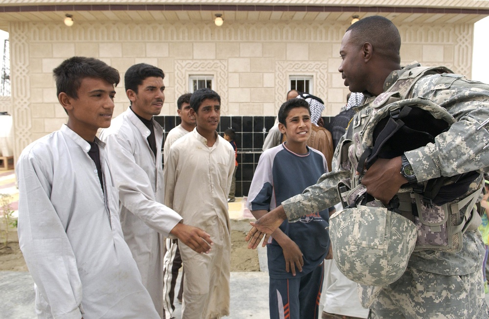A group of Iraqi boys greet U.S. Army Sgt. Maj. Benny Hubbard with handshakes.