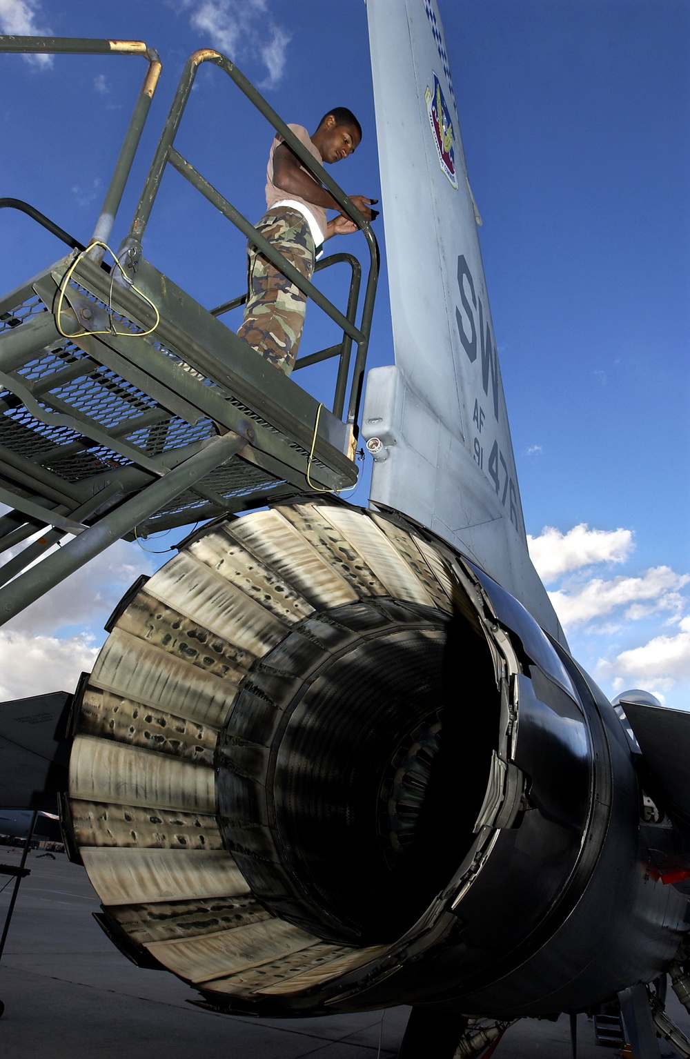 Senior Airman Benjamin Nash installs a VHF antennae on the tail of an F-16 Fighting Falcon.