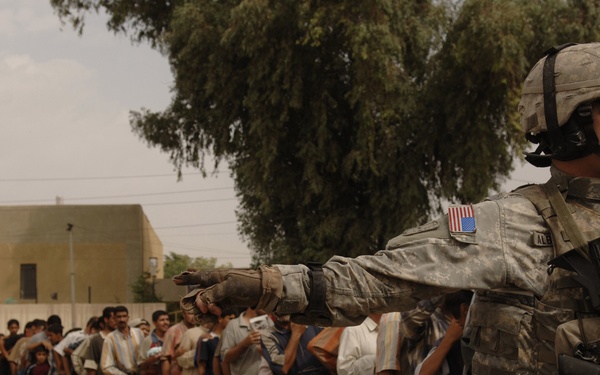 A U.S. Army soldier provides security for a long line of Iraqis.