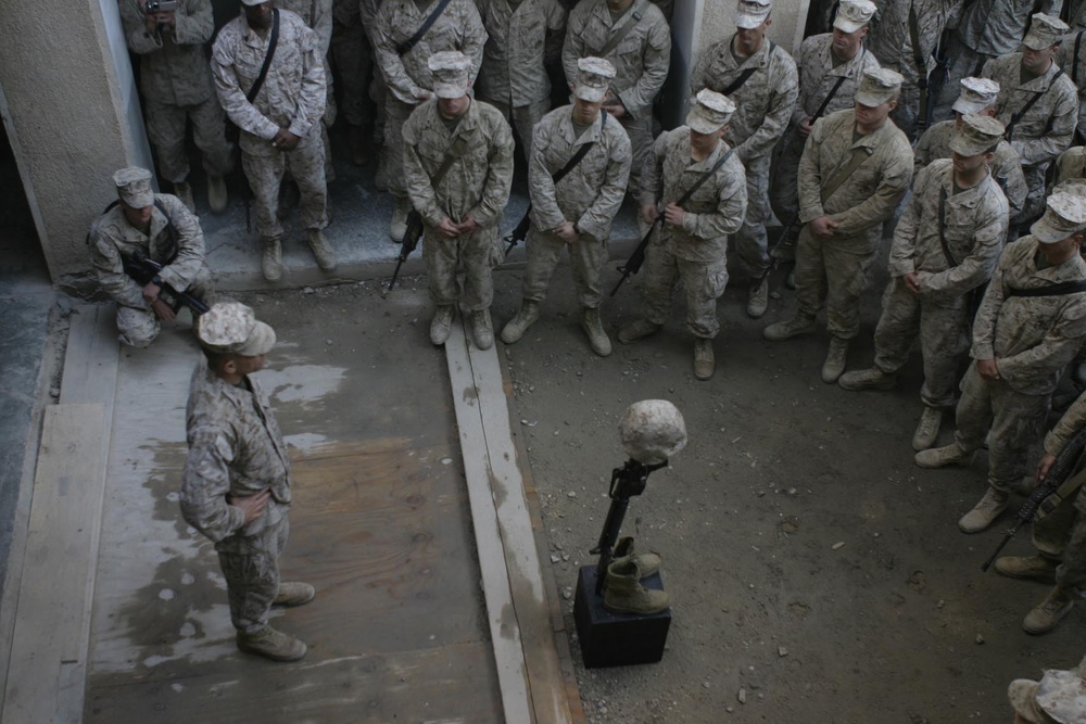 U.S. Marines gather around the boots, helmet and rifle to pay homage to a fallen Marine.