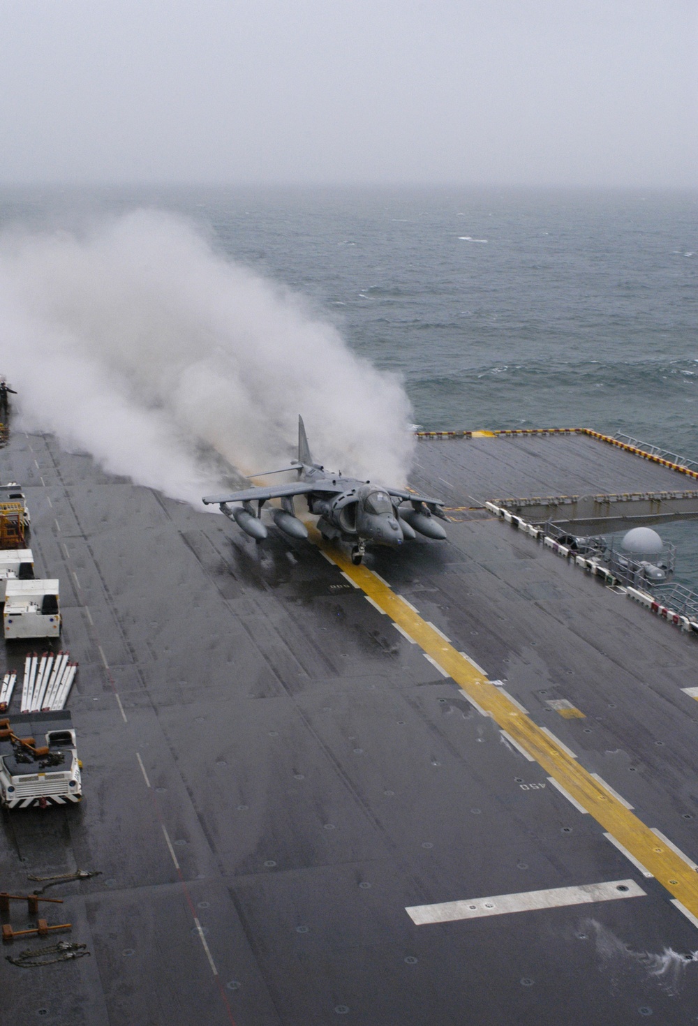 A U.S. Marine Corps AV-8B Harrier aircraft kicks up a plume of spray.