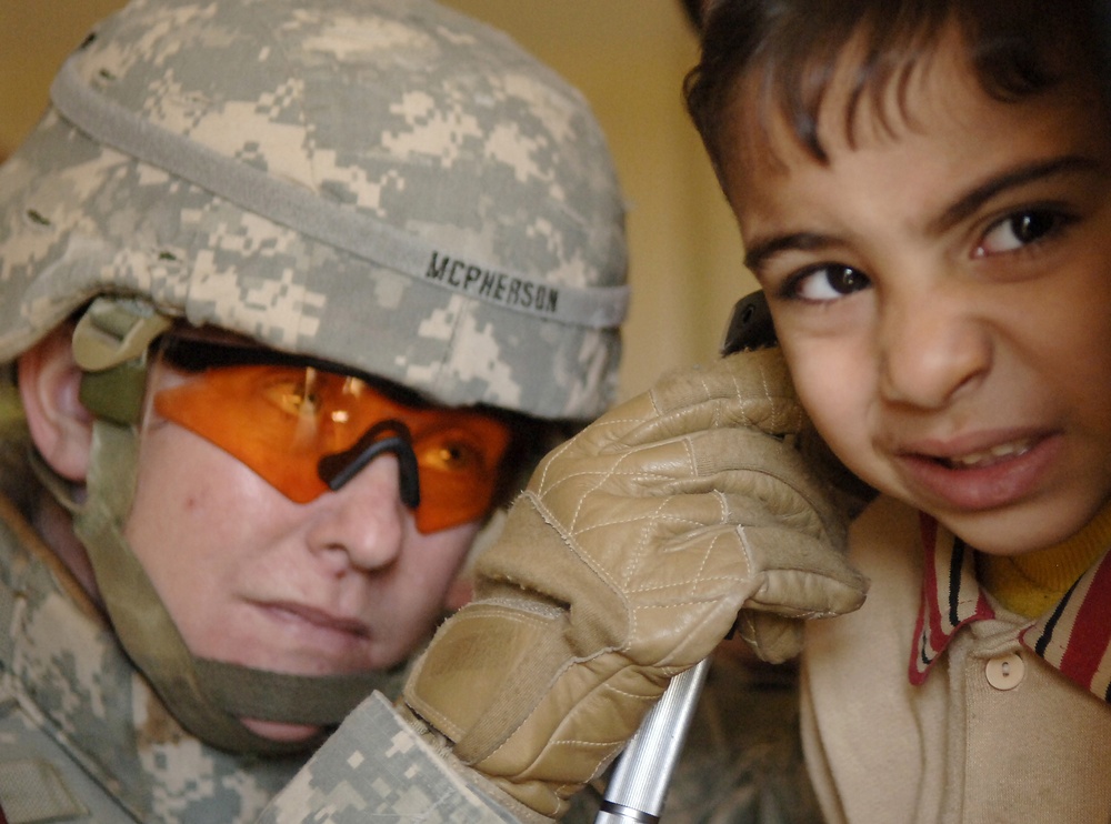 U.S. Army Capt. Cindy McPherson examines an Iraqi boy's ears.