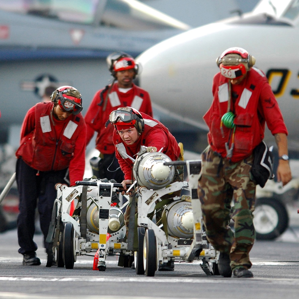 U.S. Navy personnel move carts loaded with bombs.