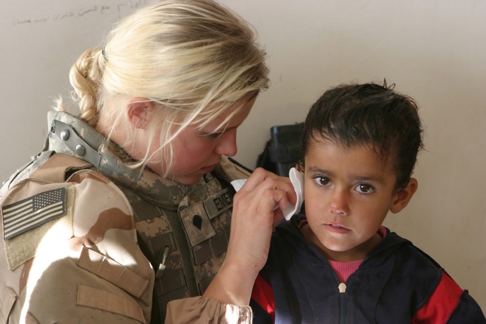 U.S. Army Spc. Taryn Emery cleans the ear of an Iraqi child.