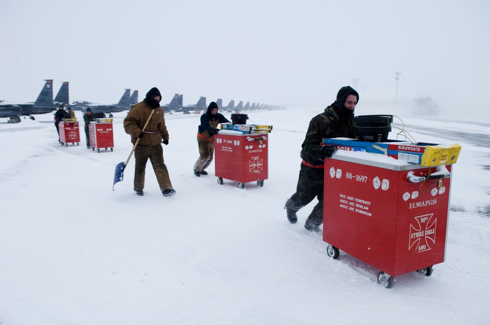 U.S. Air Force airmen push their tool chests out of the snow.