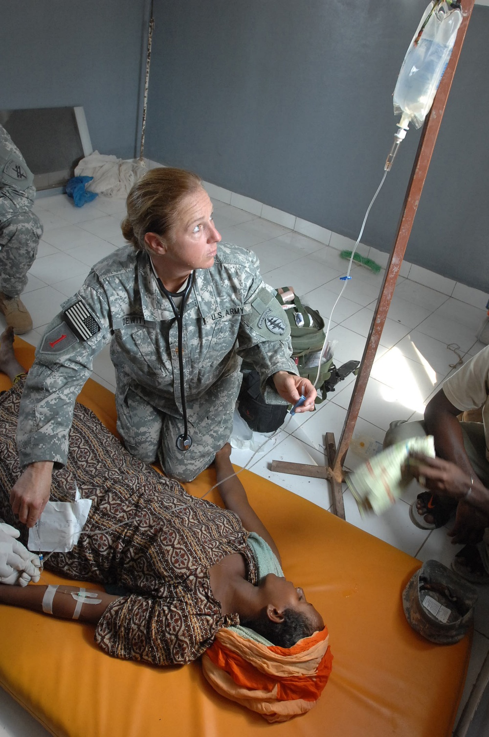Maj. Lisa J. Dewitt administers medicine to a young woman.