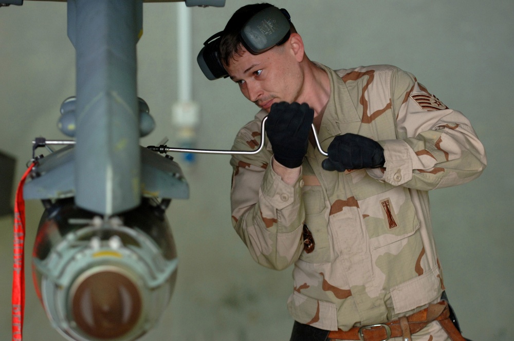 Staff Sgt. Steven Socia uses a speed wrench to secure a Joint Direct Attack Munition missile.