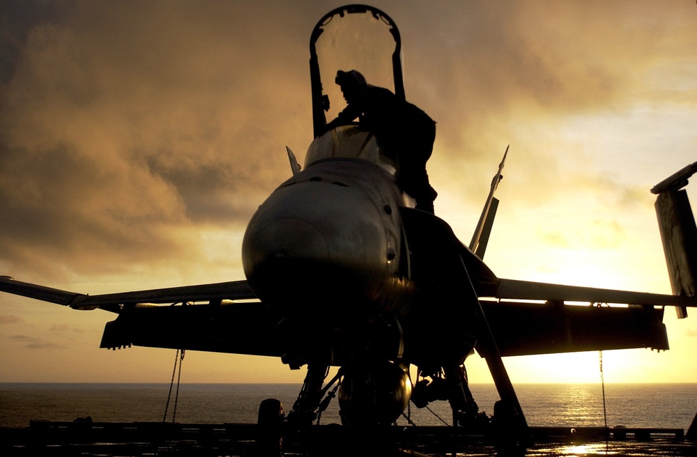 A U.S. Navy plane captain prepares an F/A-18C Hornet aircraft for flight.
