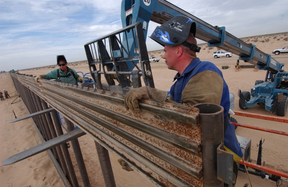 Tech. Sgts. Brad Bird and Brian Schumacher position a steel panel.