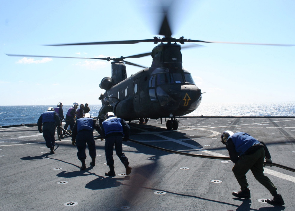 U.S. Navy sailors prepare to refuel an Army CH-47 Chinook helicopter.