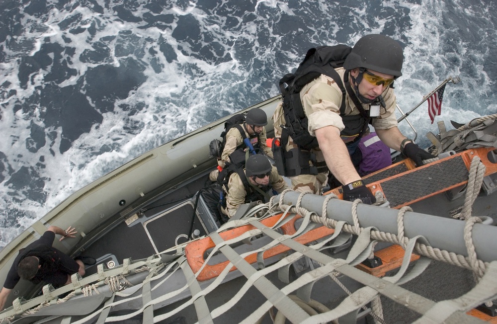 Petty Officer 3rd Class James Cauble climbs aboard the USS Mustin (DDG 89).
