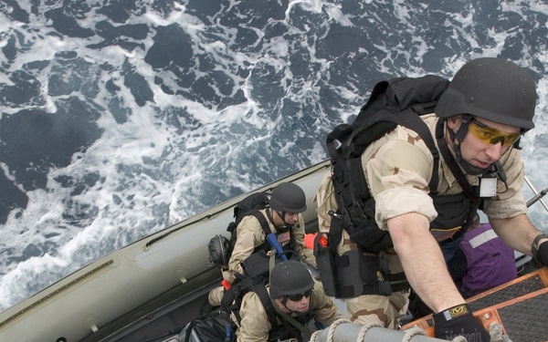 Petty Officer 3rd Class James Cauble climbs aboard the USS Mustin (DDG 89).