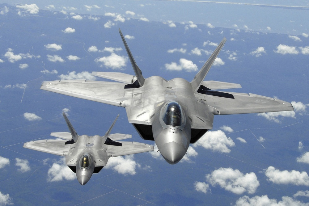 Two U.S. Air Force F-22 Raptor aircraft fly in trail behind a KC-135R Stratotanker.