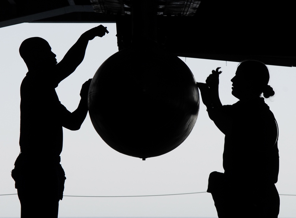 Petty Officer 2nd Class Turner and Petty Officer 3rd Class Wallace secure the mounts on a fuel drop tank.