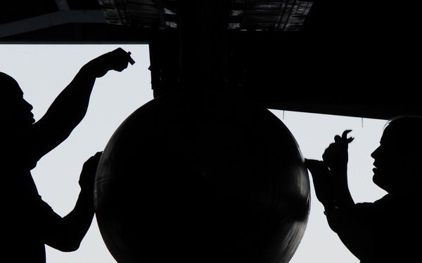 Petty Officer 2nd Class Turner and Petty Officer 3rd Class Wallace secure the mounts on a fuel drop tank.