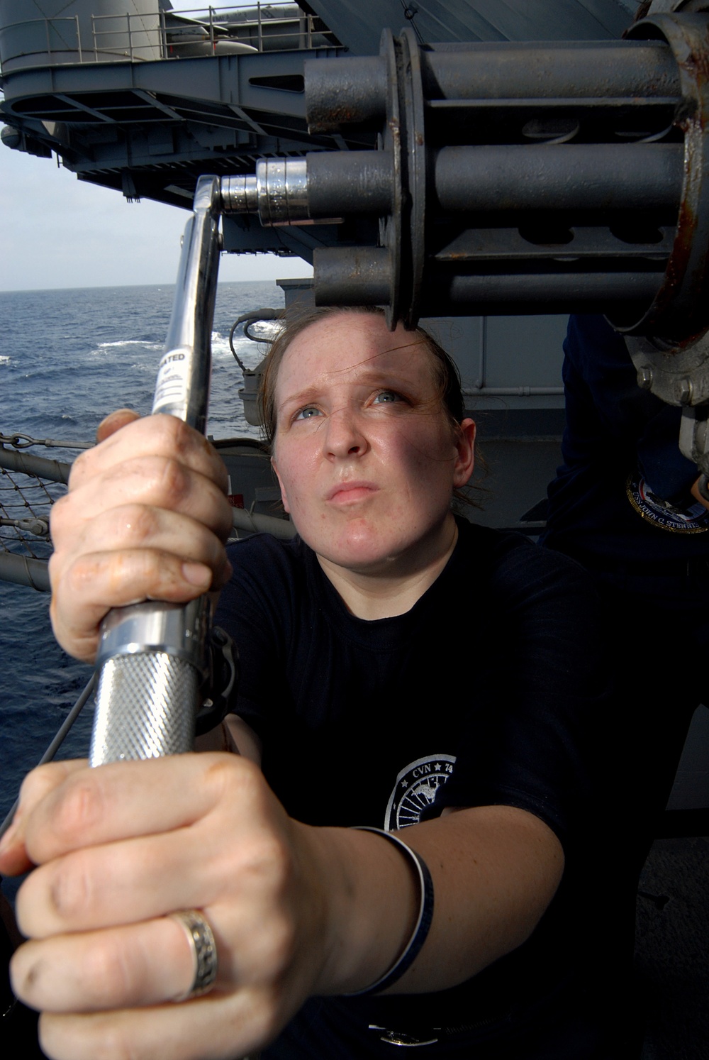Petty Officer 3rd Class Geneva Myers ensures that the barrels of the close-in weapons system are tight.