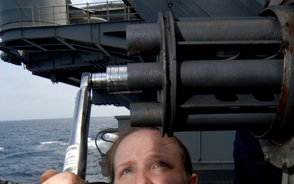Petty Officer 3rd Class Geneva Myers ensures that the barrels of the close-in weapons system are tight.