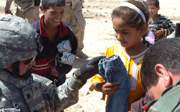 Lt. Col. Guy Edmondson (left) hands out clothing to village children.