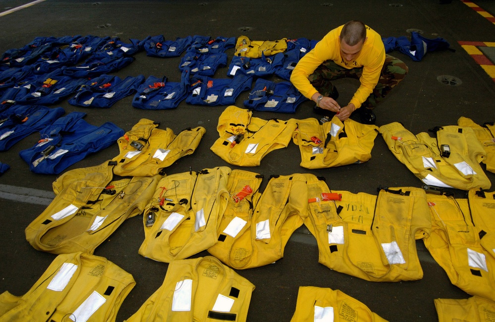 Petty Officer 3rd Class Louis Perone goes through each float coat.