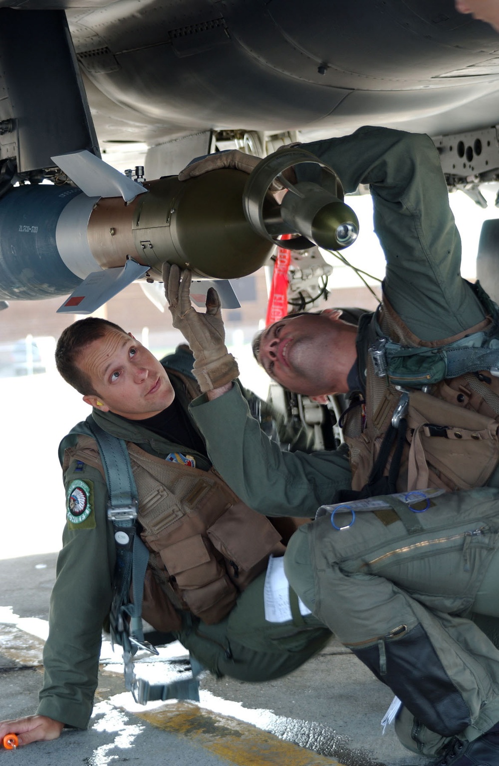 Capt. Chris Beery watches Capt. Kevin Pritz perform a pre-flight check on an F-15E.