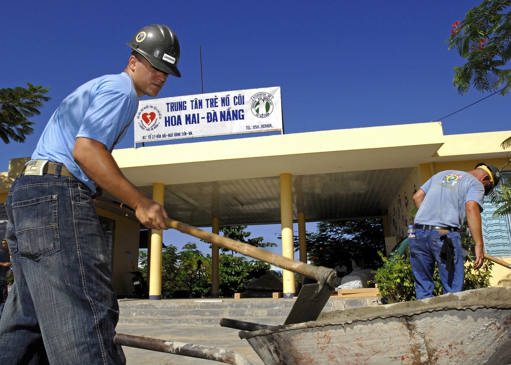 Seabee Petty Officer 3rd Class Brian Laferriere mixes cement for a playground.