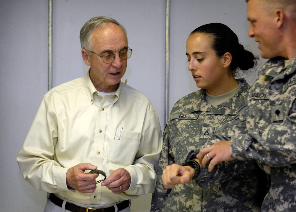 A soldier gives Deputy Secretary England a bracelet.