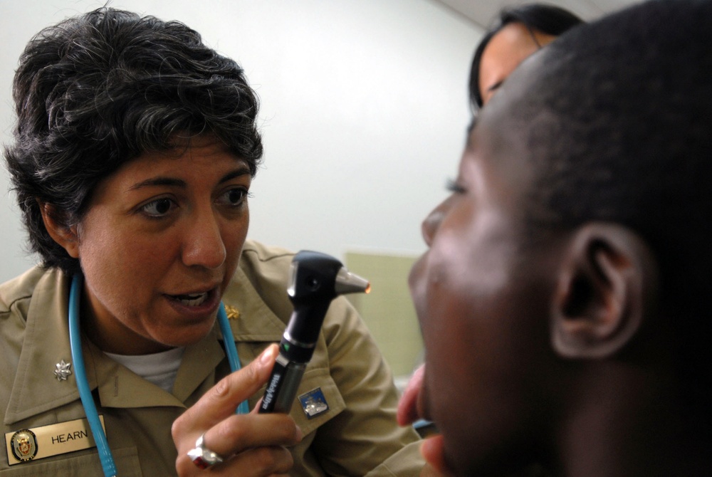 Cmdr. Sandra Hearn inspects a patient's throat.