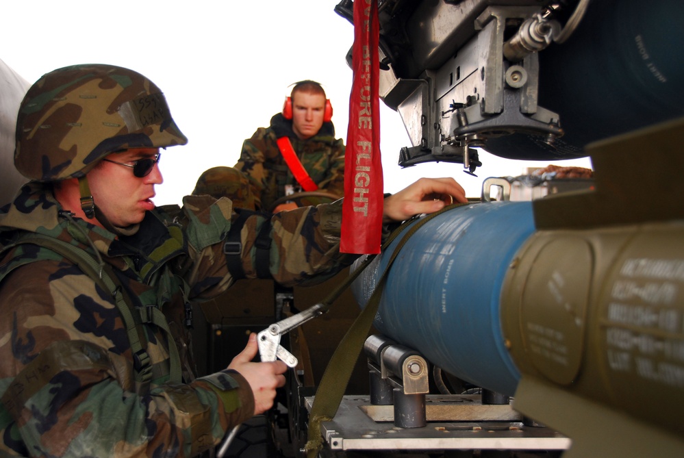 Staff Sgt. Mikel Parrish (left) and Airman 1st Class Patrick Ward load a BDU-50 practice bomb.
