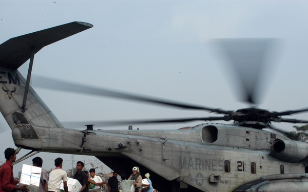 Bangladeshi men and U.S. Marines pass boxes of food from hand-to-hand.