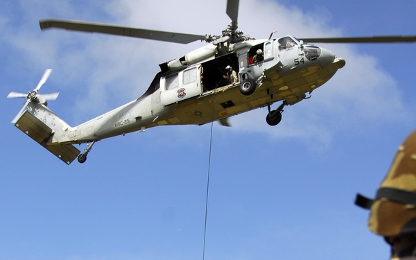 Airmen watch as a fellow team member repels from an HH-60 Pave Hawk helicopter.