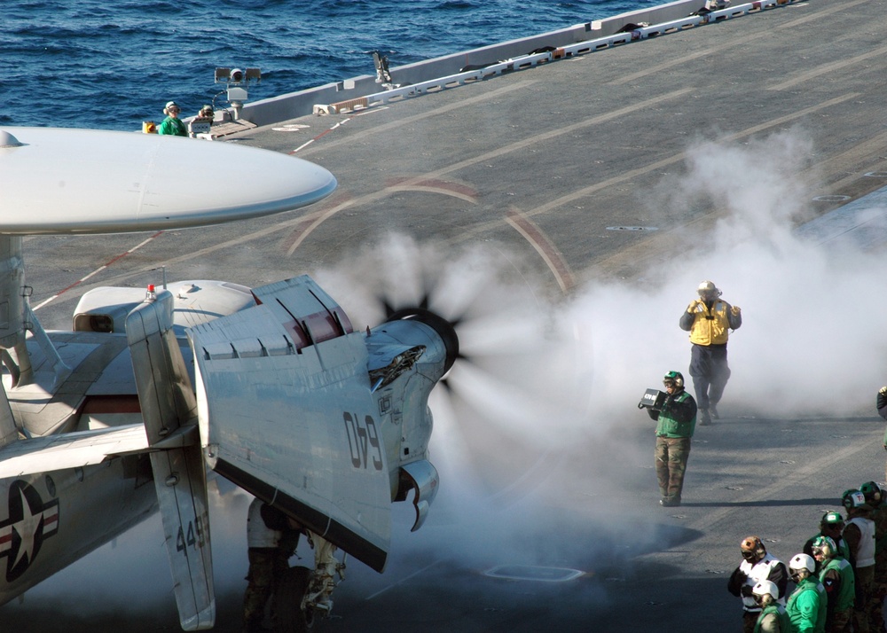 A U.S. Navy Aviation Boatswain's Mate (Handling) directs an E-2C Hawkeye.