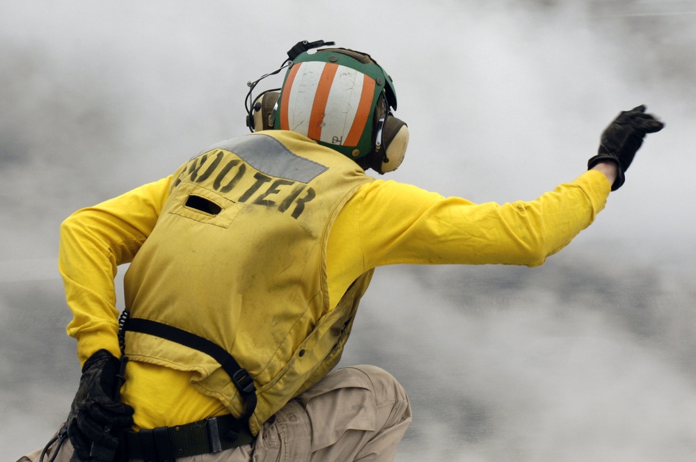 Lt. Dustin Hendrix signals through the steam for the catapult launch of an aircraft.