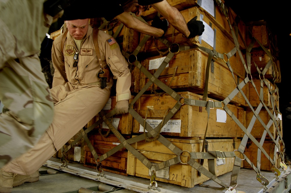 Tech. Sgt. Mark Blinn and Iraq air force airmen push a pallet of ammunition into an Iraqi air force C-130 Hercules aircraft.