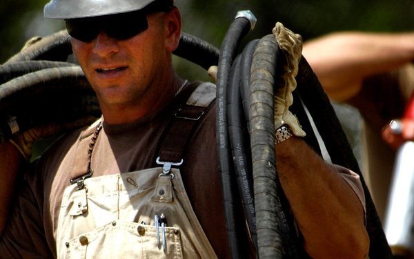 Petty Officer 1st Class Steven Barczak unloads hoses from a truck.