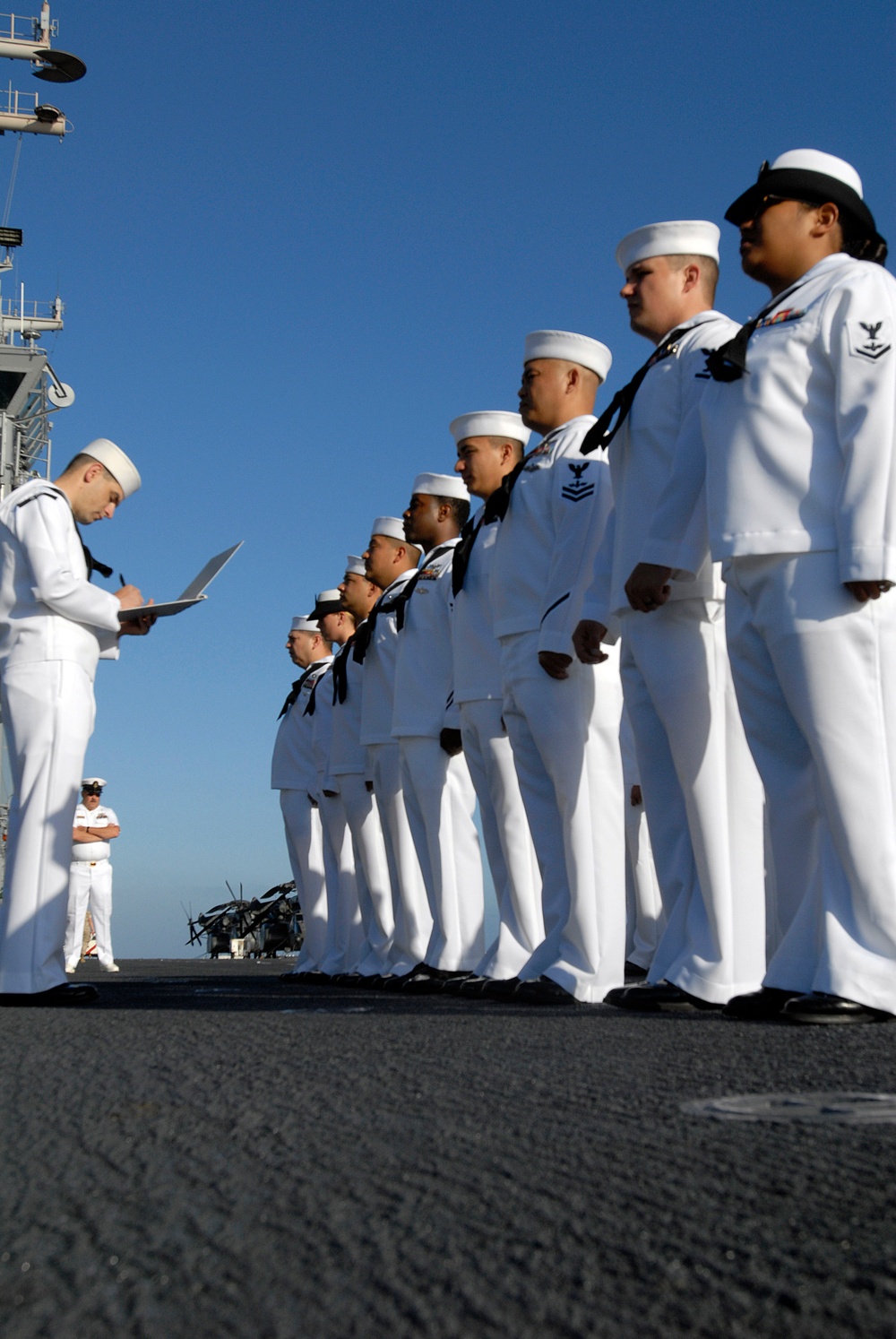 U.S. Navy sailors stand in formation during a uniform inspection.