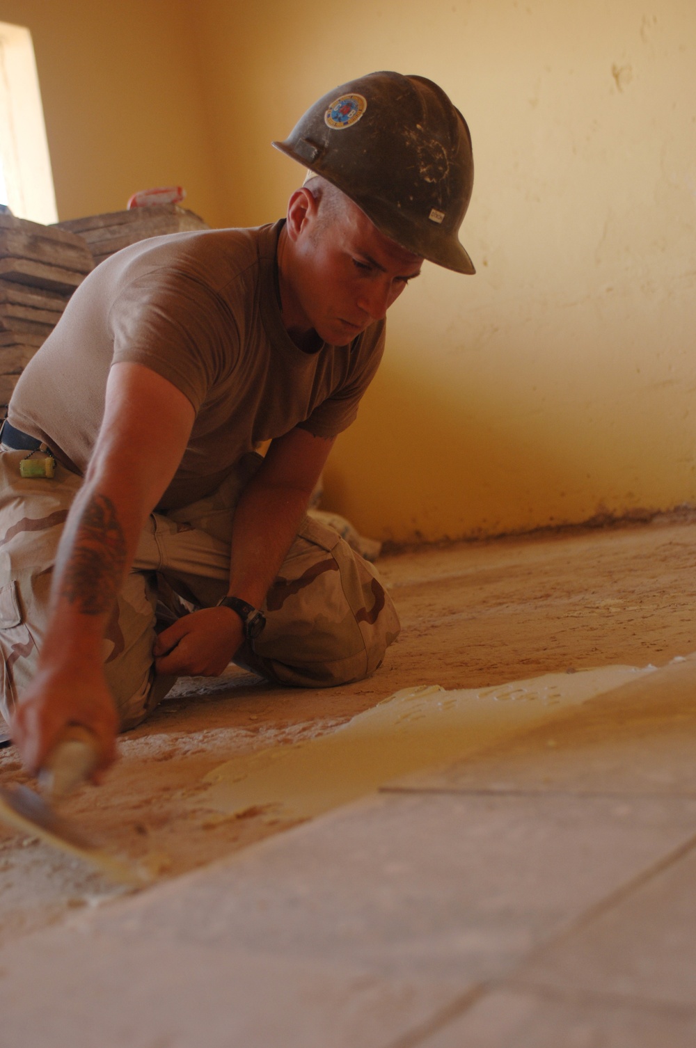 Petty Officer 3rd Class Patrick Dixon applies mortar to the floor.